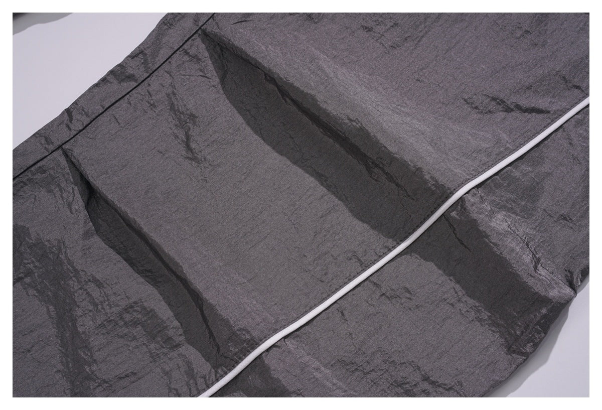 Close-up showing a pleated panel and white piping on the charcoal gray pants.