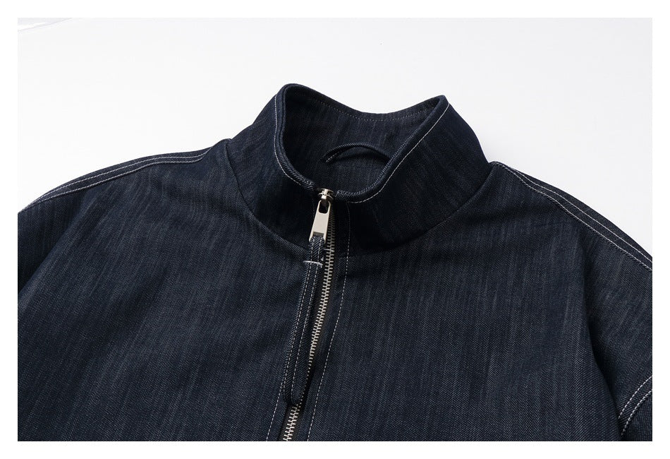 Upper section of a dark indigo jacket showing its stand collar, front zipper, and contrast stitching.