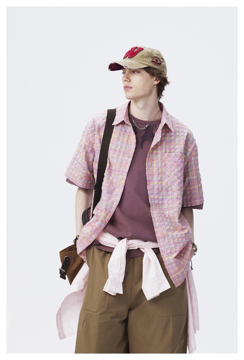 Closer view of a model wearing an open pastel pink plaid short-sleeve shirt with a single chest pocket.
