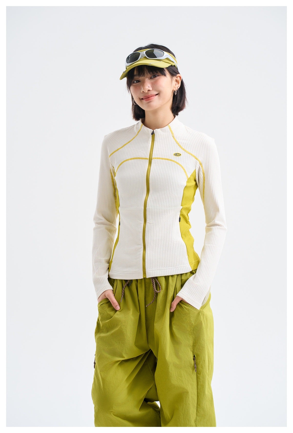 Model wearing a white textured zip-front jacket with bright yellow seam accents and side panels.