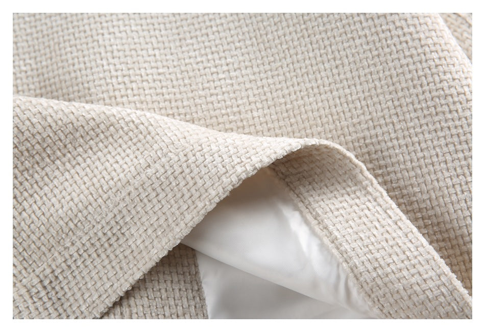 Close-up of cream woven garment fabric folded back to reveal a smooth white lining.