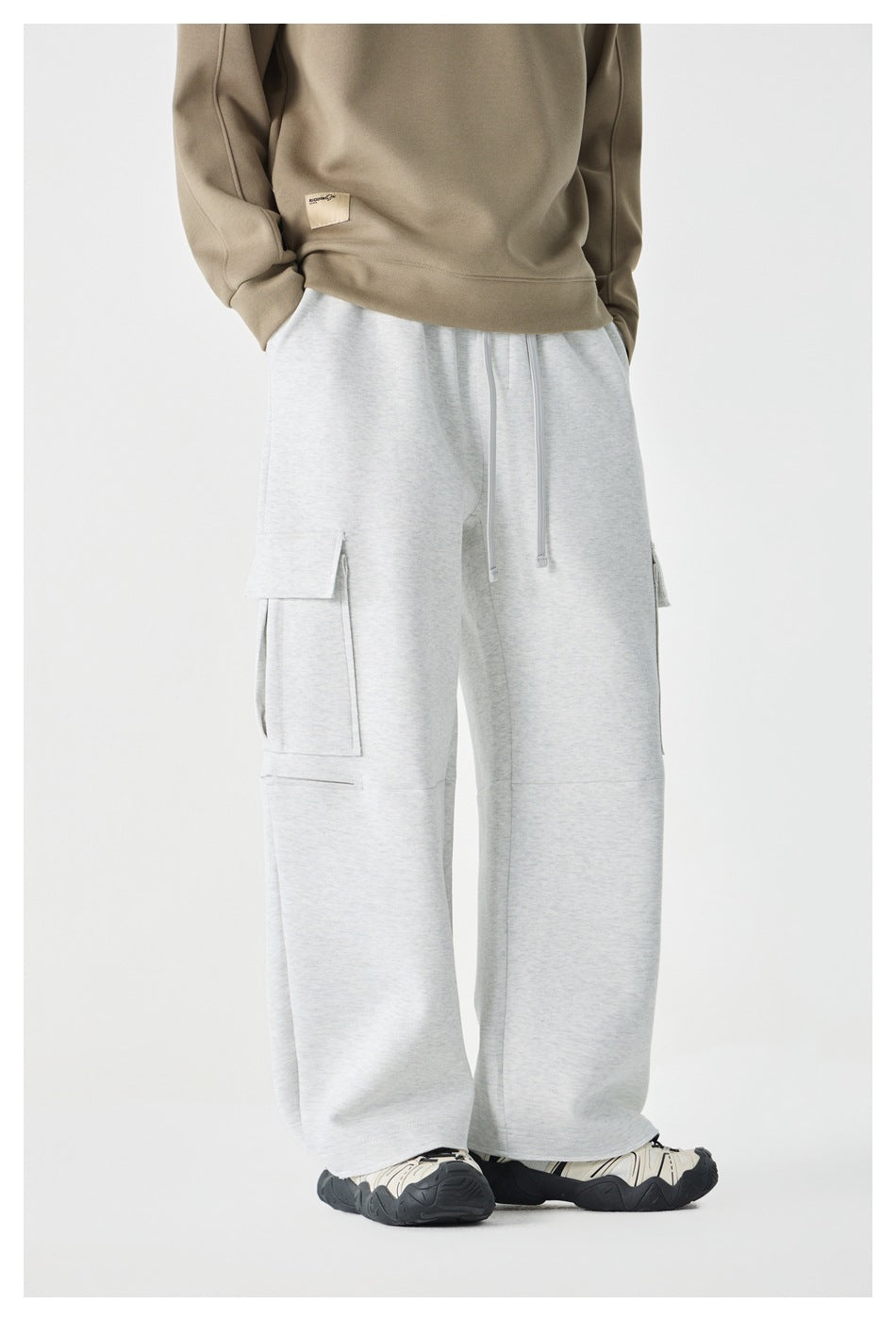 Front angled view of a model wearing light gray wide-leg cargo pants with drawstrings and flap pockets.