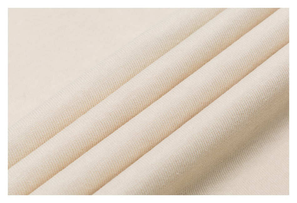Close-up of pale cream fabric folded into ridges, showing a fine textured knit surface.