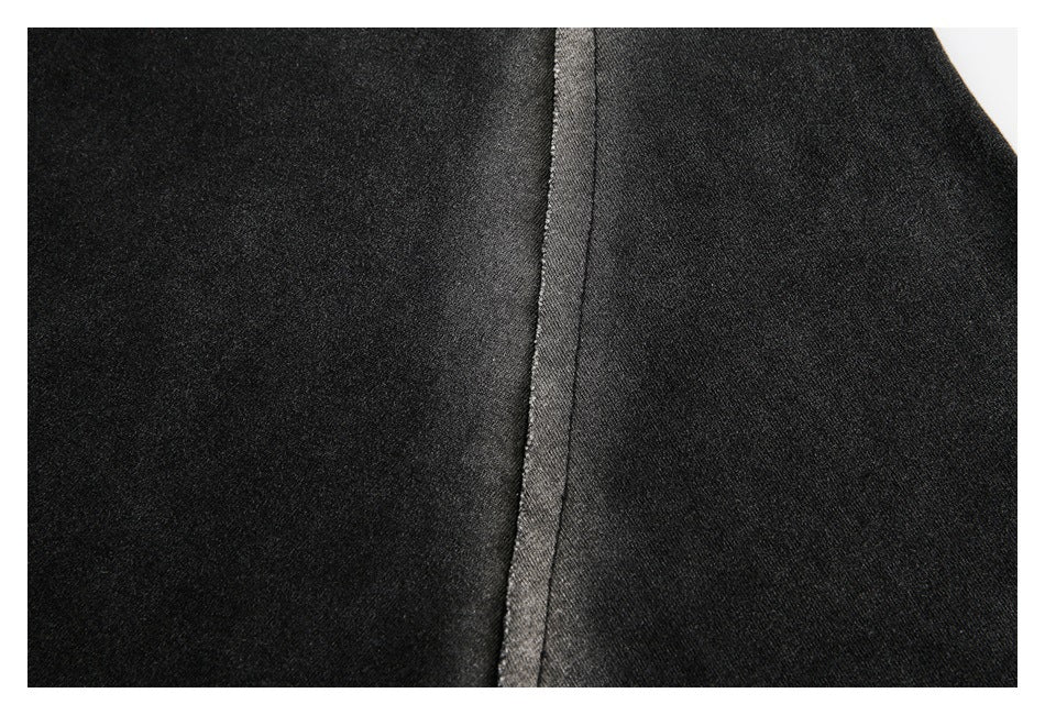 Close-up of dark garment fabric showing a vertical seam and contrasting panel edges.