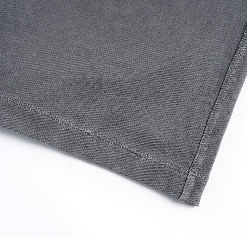 Close-up of the stitched hem and side seam on gray shorts.