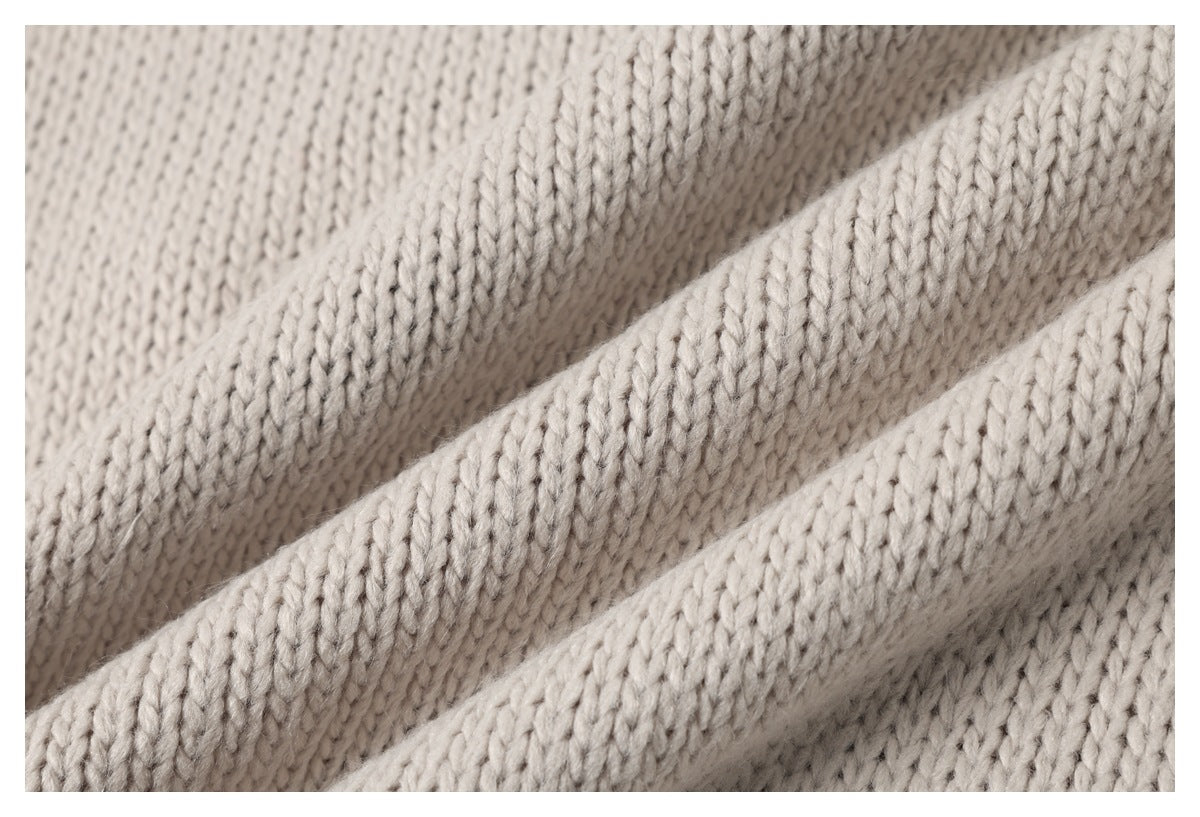 Macro view of cream knit fabric arranged in soft folds, showing the stitch texture.