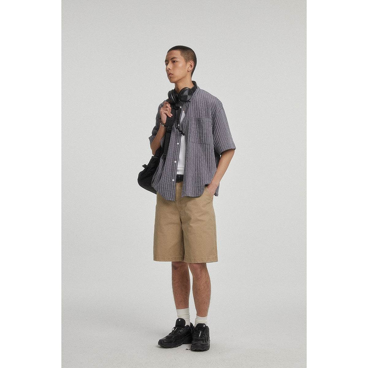 Model wearing tan knee-length shorts with a charcoal pinstriped short-sleeve shirt.