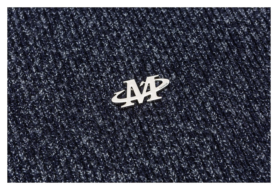 Close-up of a metal badge on navy marled knit fabric.