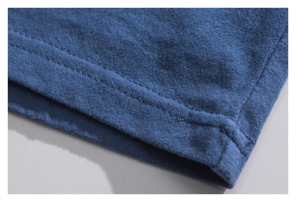 Close-up of the blue T-shirt's stitched bottom hem and fabric edge.