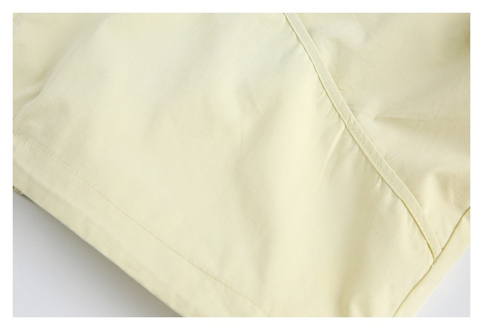 Close-up of pale yellow garment fabric with stitched seams and a narrow bound edge.