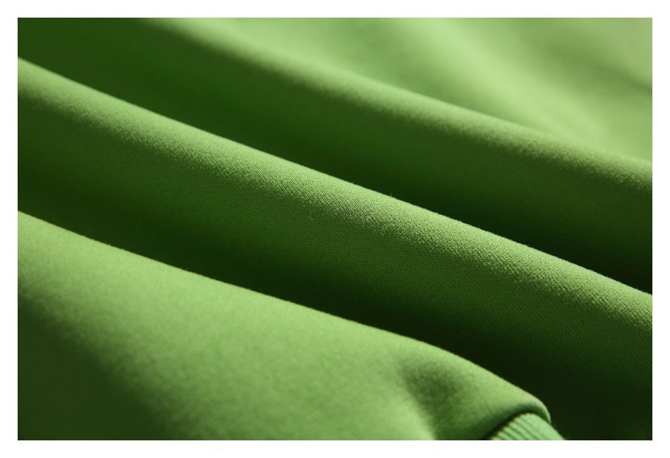 Close-up of green fabric folded into diagonal ridges, with a fine, even texture.