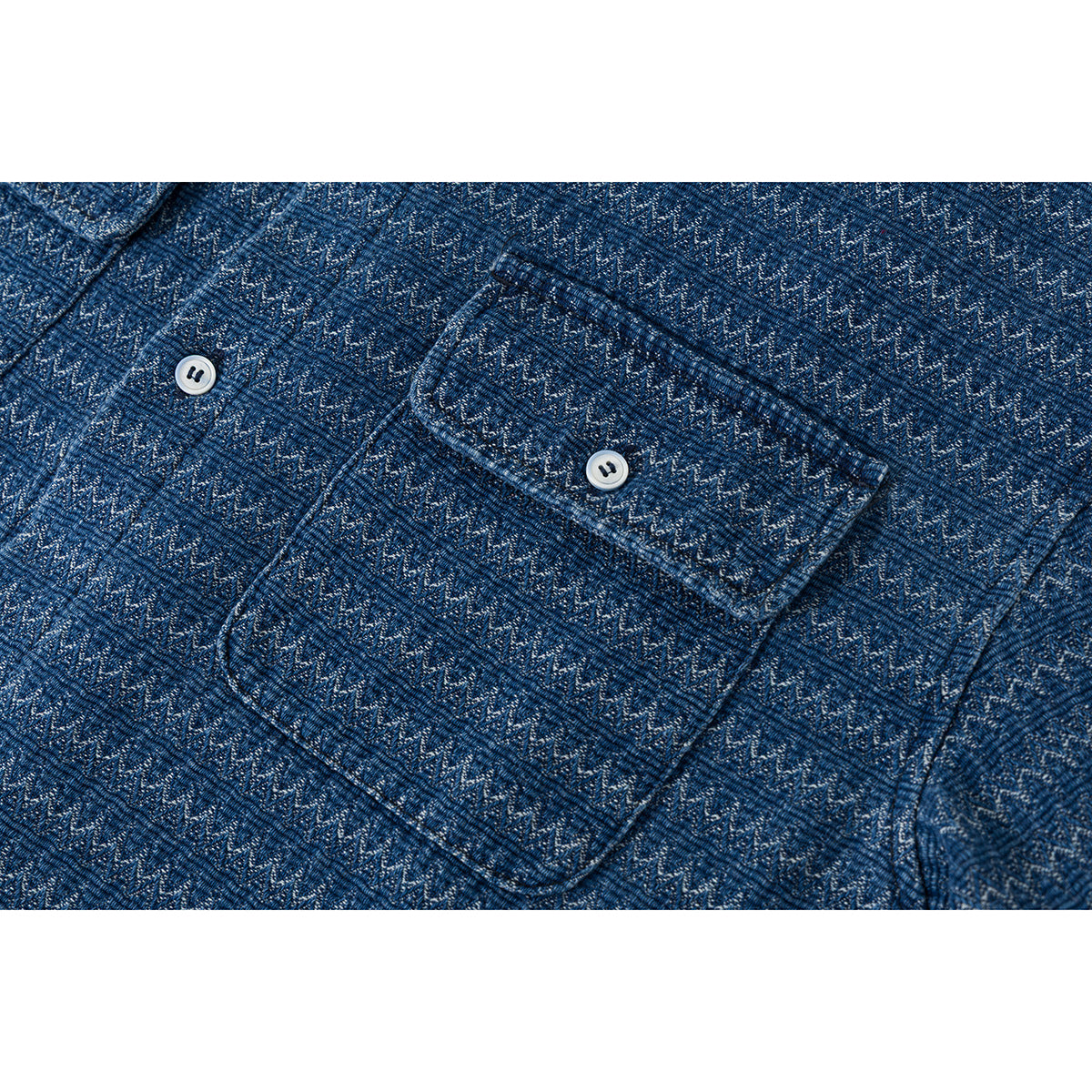 Close-up of a blue patterned shirt pocket with a button and matching zigzag fabric.
