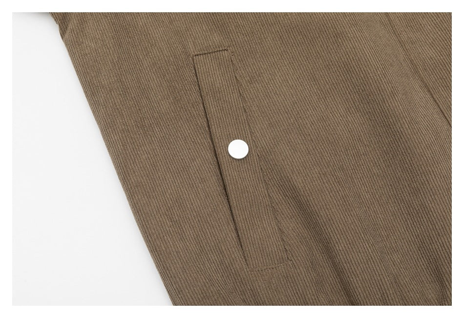 Close-up of a taupe jacket pocket with a vertical opening and a round snap button.