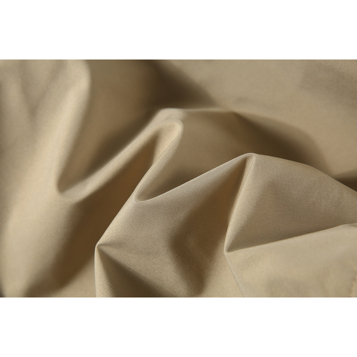 Macro view of tan jacket fabric draped into folds, showing its fine woven surface.