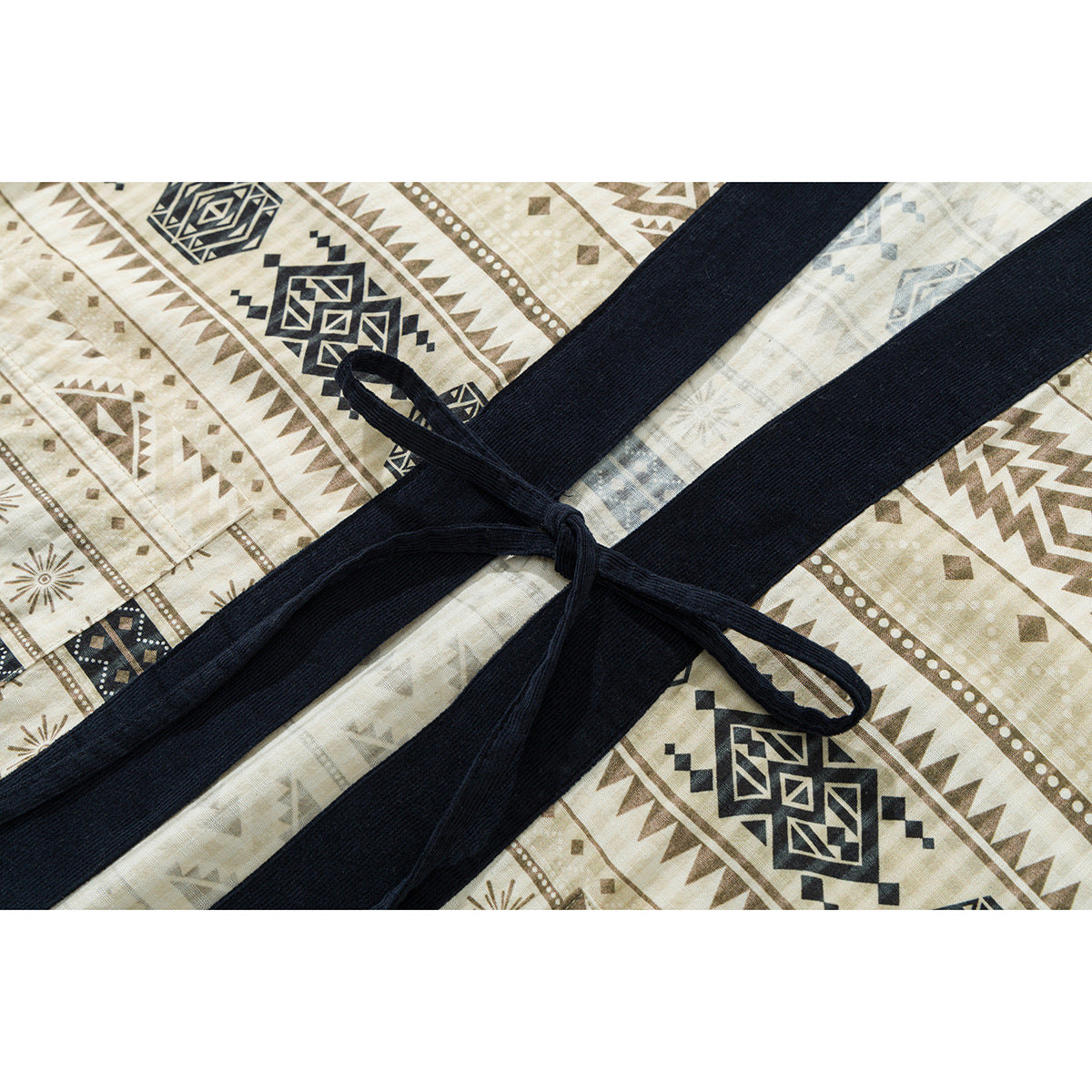 Close-up of the shirt's dark navy waist tie over cream fabric with brown and navy geometric bands.