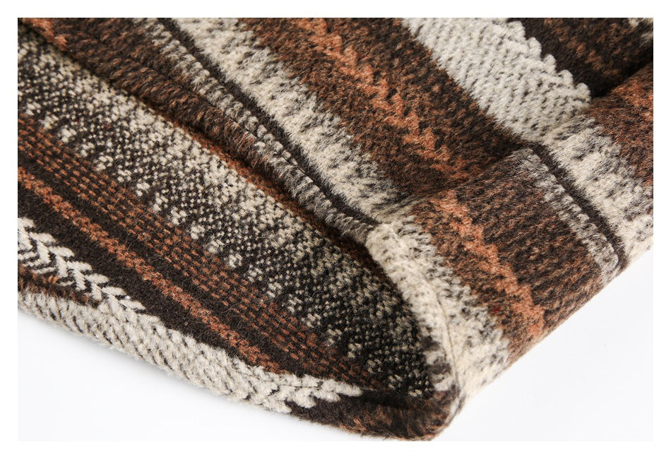 Close-up of the folded edge and plaid pattern on a brown, rust, cream, and dark garment.