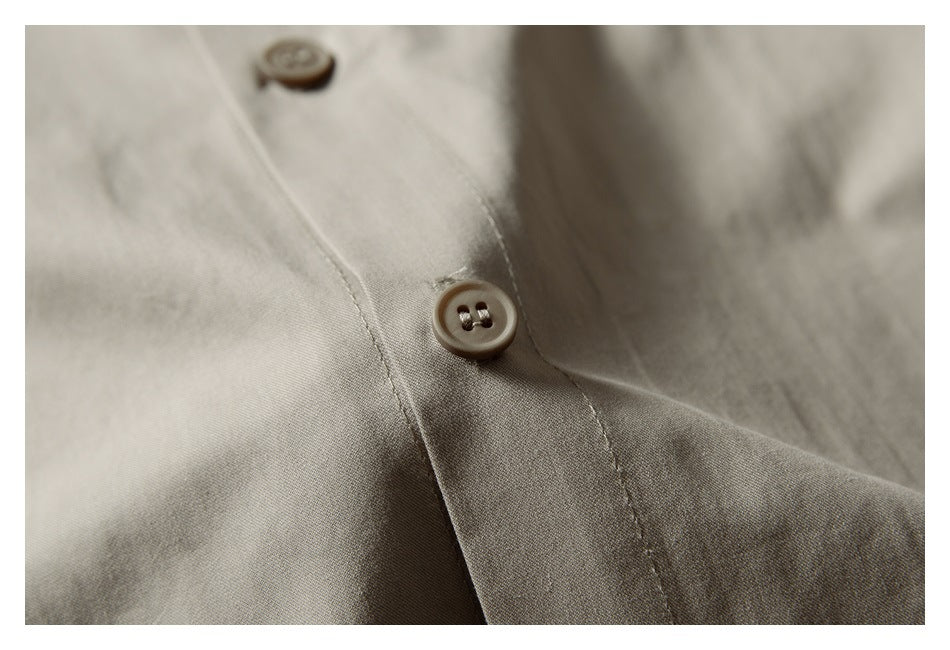 Close-up of a beige garment's button placket with a brown four-hole button and stitched seams.