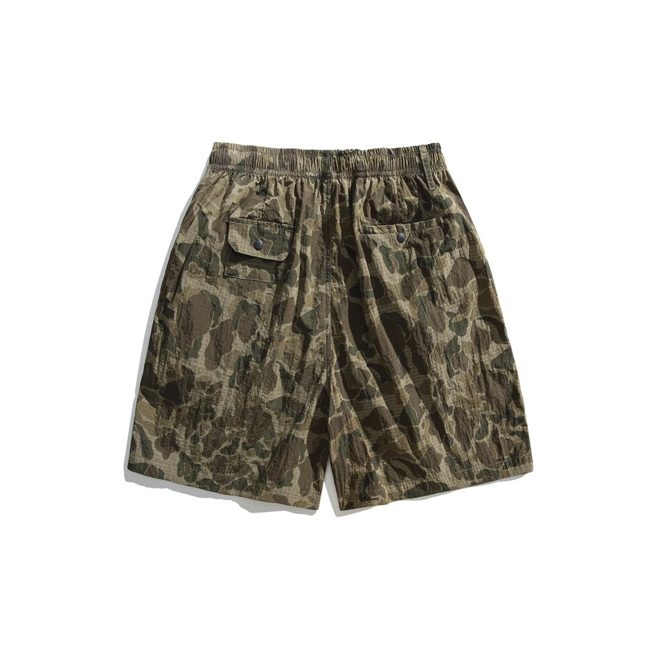 Back view of olive and brown camouflage shorts with an elastic waistband and two buttoned pockets.