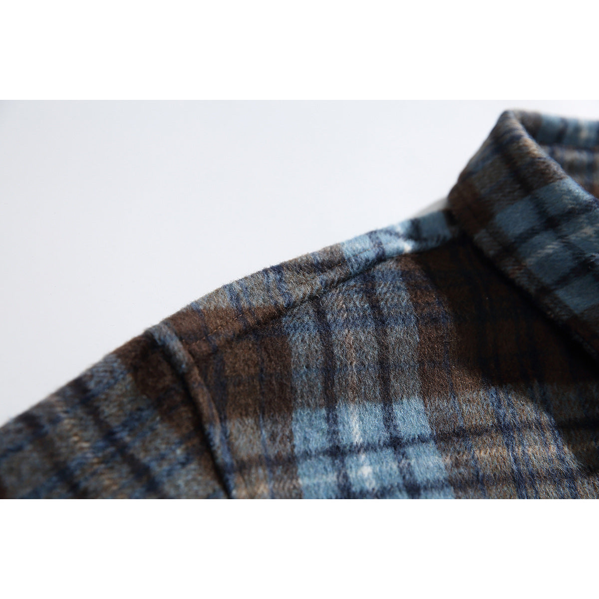 Close-up of the shoulder and collar of a blue and brown plaid shirt, showing its brushed-looking surface.