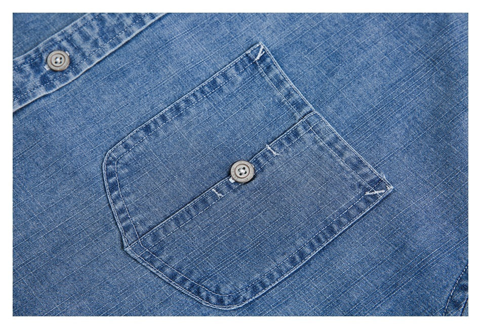 Close-up of a blue shirt's buttoned chest pocket and surrounding fabric.
