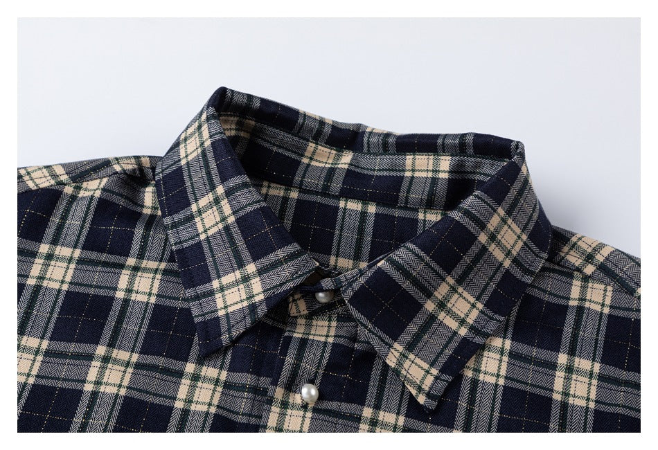 Close-up of the navy and cream plaid shirt collar and upper placket with a pearl-like button.