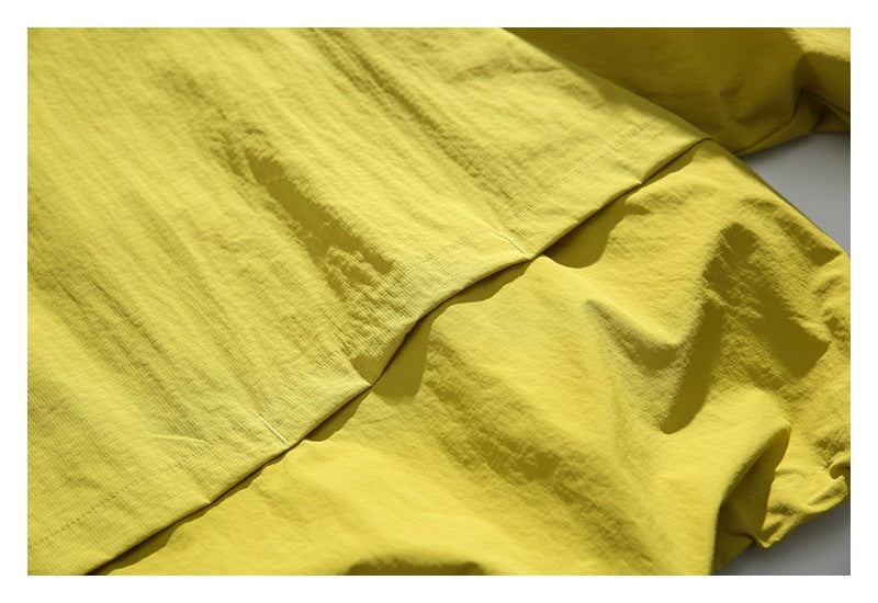 Close-up of overlapping yellow-green jacket fabric panels and stitching.