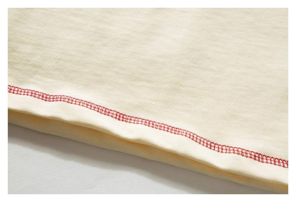 Close-up of a cream garment hem with red overlock stitching along the edge.