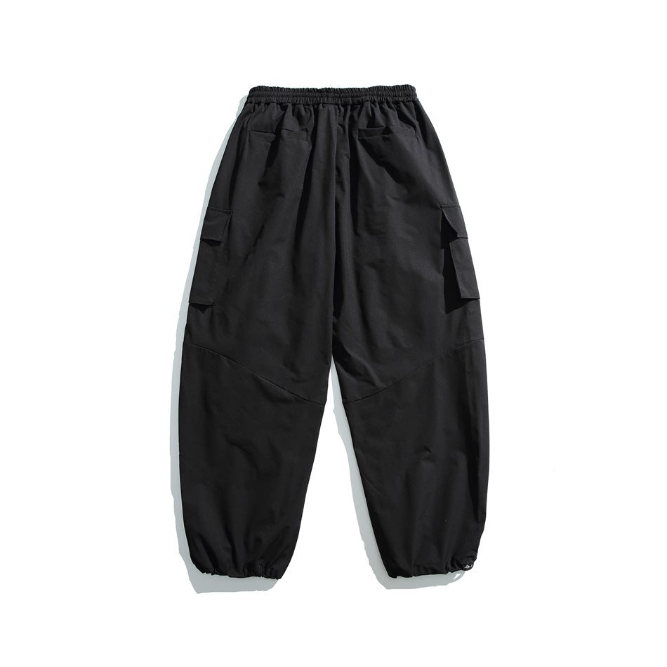 Back view of black cargo pants with an elastic waistband, rear pockets, flap side pockets, and gathered cuffs.