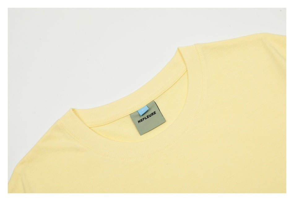 Close-up of the pale yellow T-shirt crew neck and attached label.