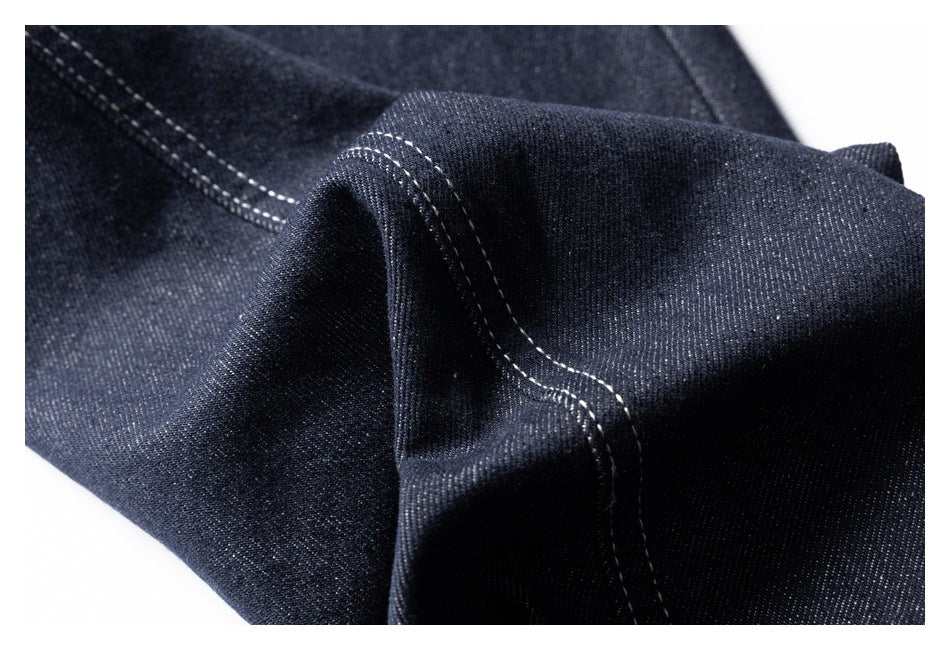 Close-up of dark denim folded to show a raised seam with contrast stitching.