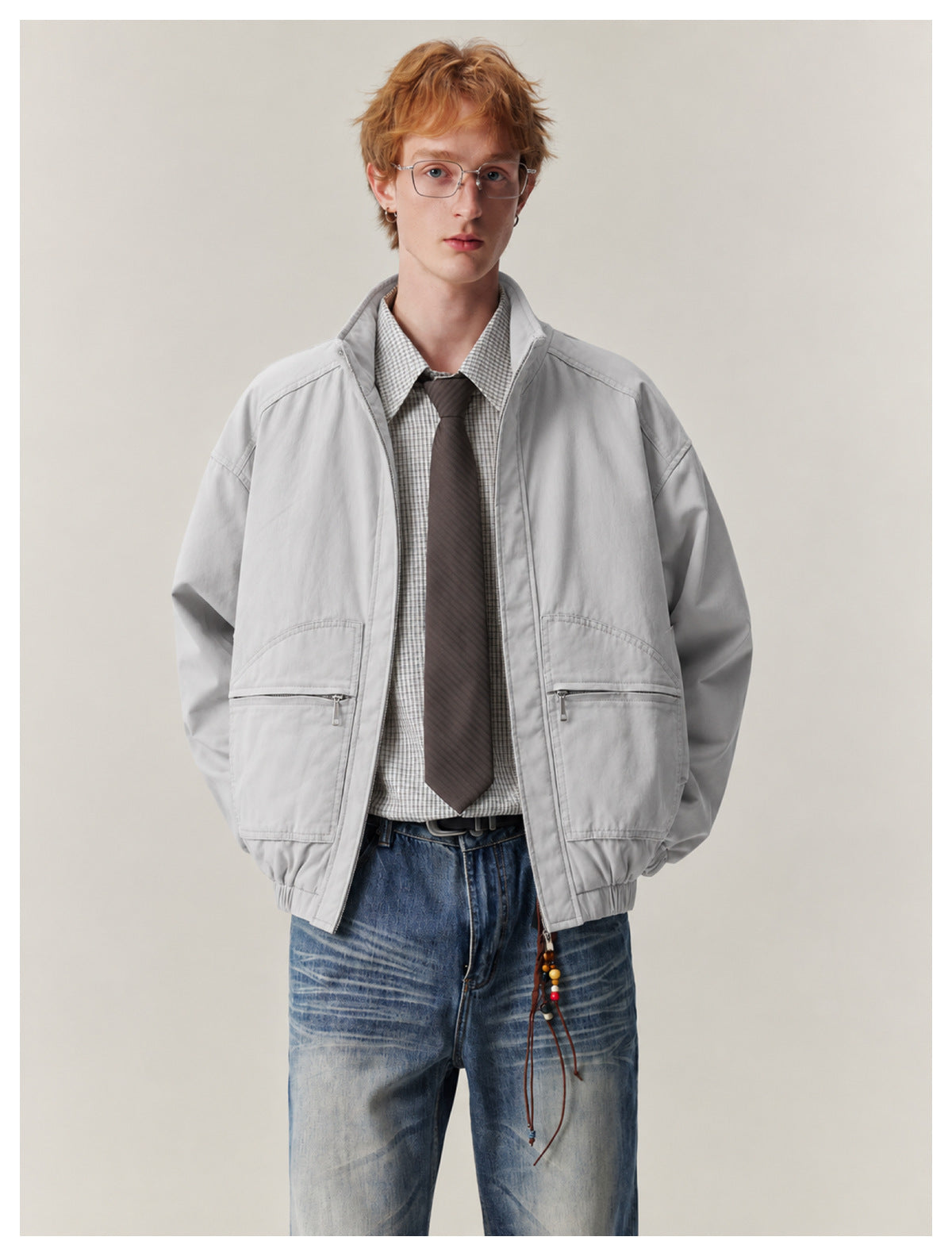 Model wearing a light gray zip jacket with a stand collar and large front zip pockets.