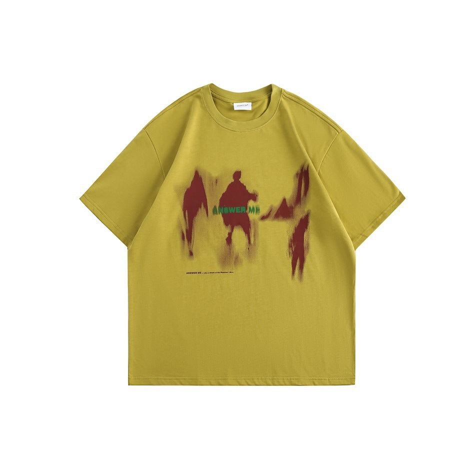 Yellow short-sleeve crew-neck T-shirt with blurred red figure graphic and green 'ANSWER ME' lettering, flat lay