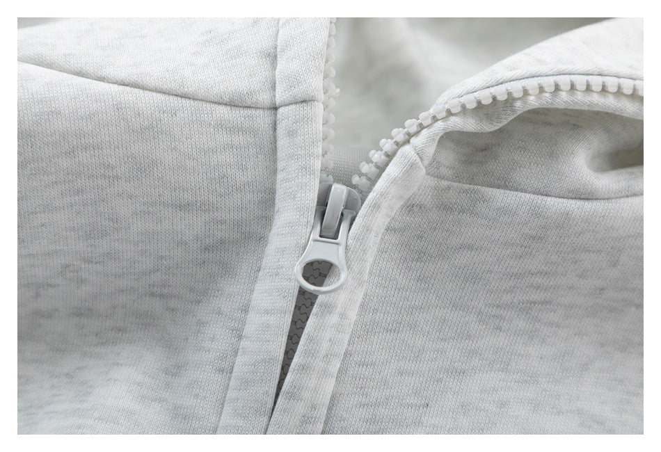 Close-up of a light gray plastic zipper and zipper pull on heather-gray hoodie fabric.
