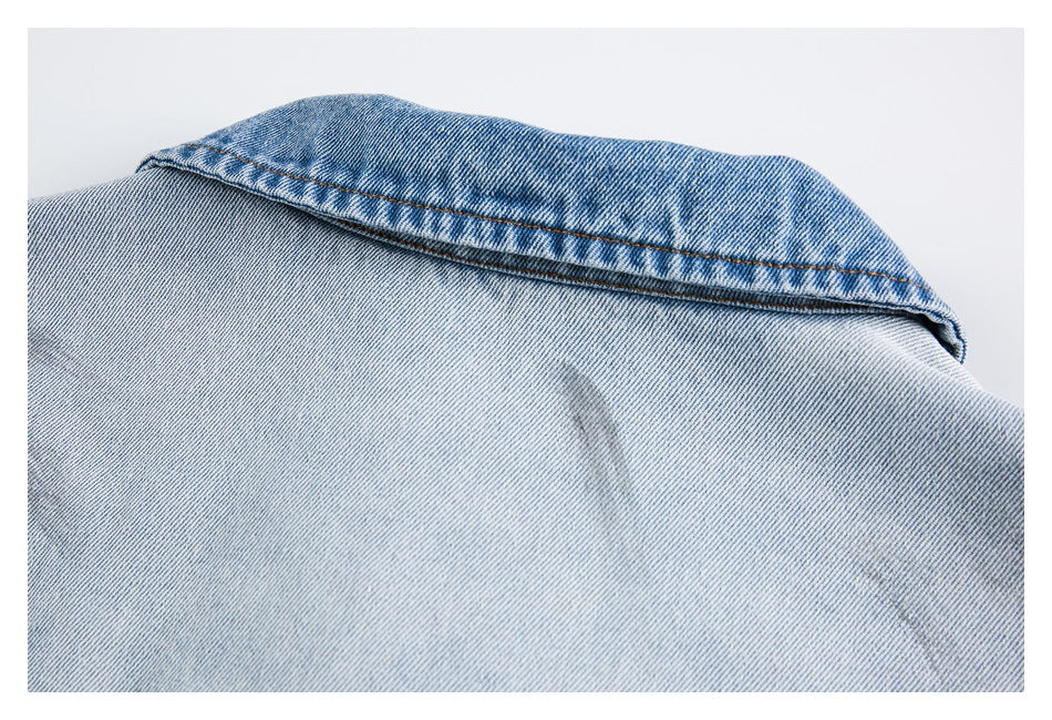 Close-up of a light blue denim jacket collar with contrasting brown topstitching.