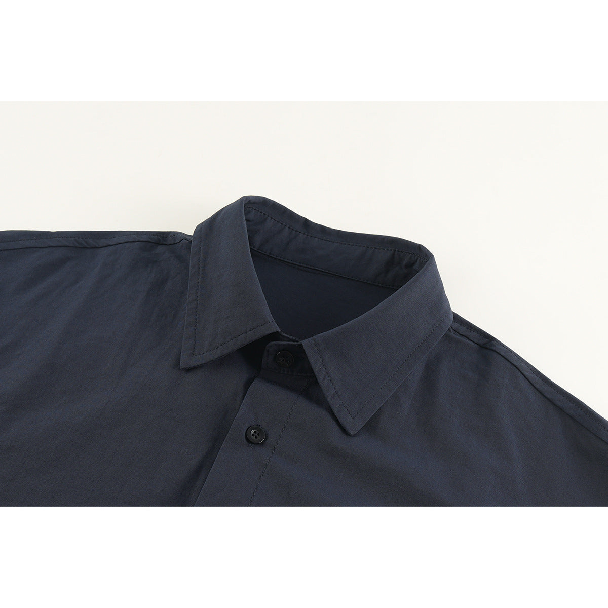 Close-up of a dark navy button-up shirt collar, shoulder seams, and front buttons.