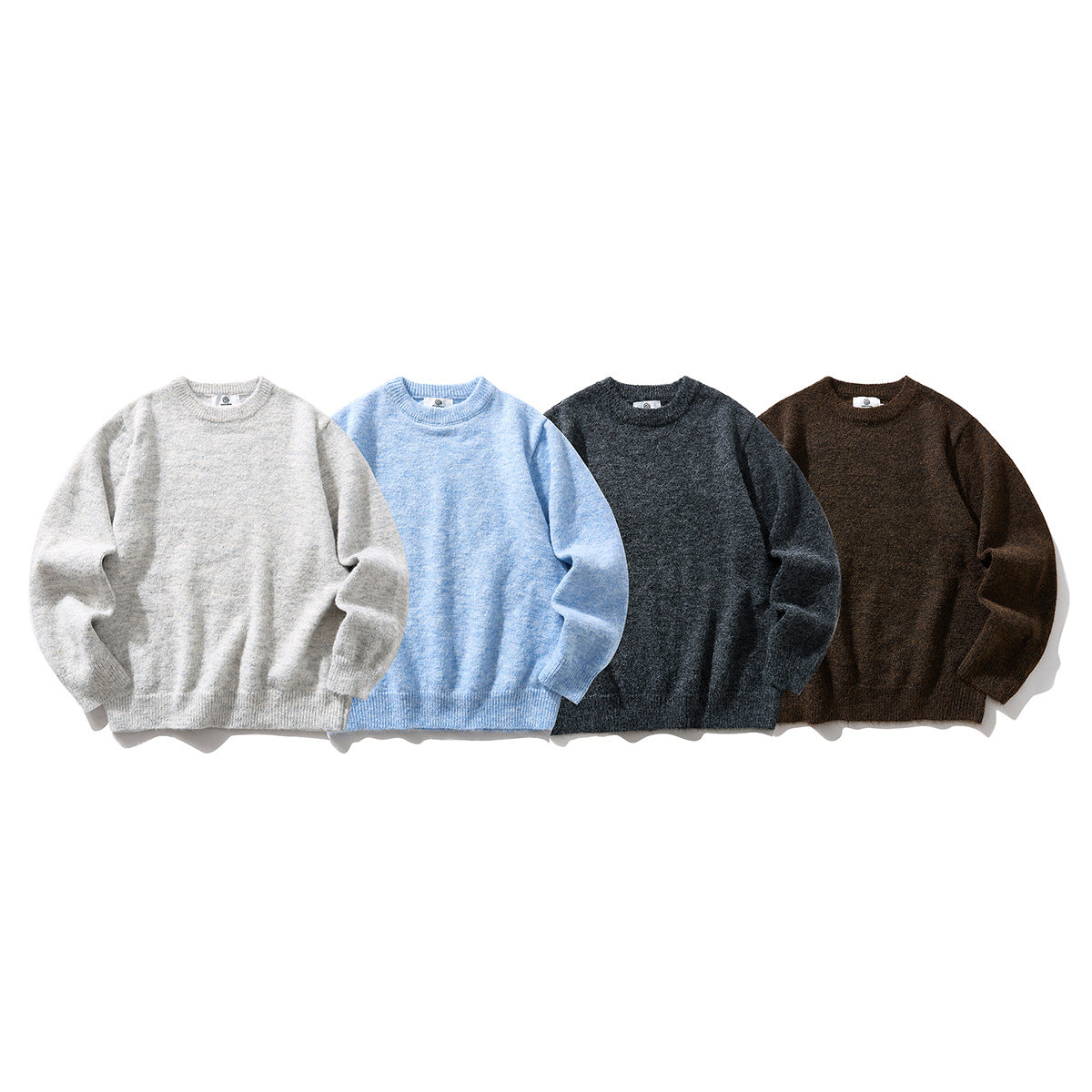 Four crewneck knit sweaters shown from the front in light gray, pale blue, charcoal, and brown.