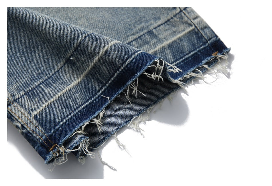 Close-up showing the heavily frayed raw hem of light-wash denim shorts.
