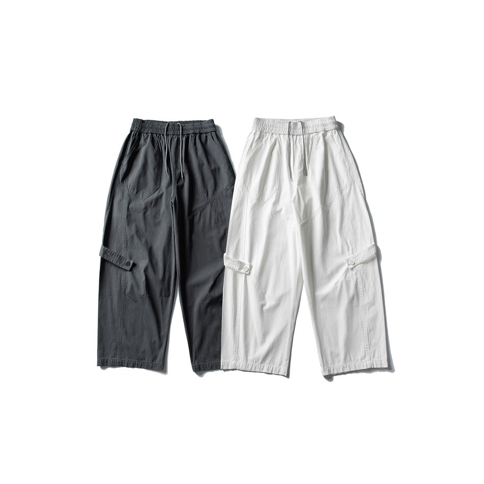 Two pairs of wide-leg cargo pants shown from the front, one charcoal and one white, with elastic waists and drawcords.