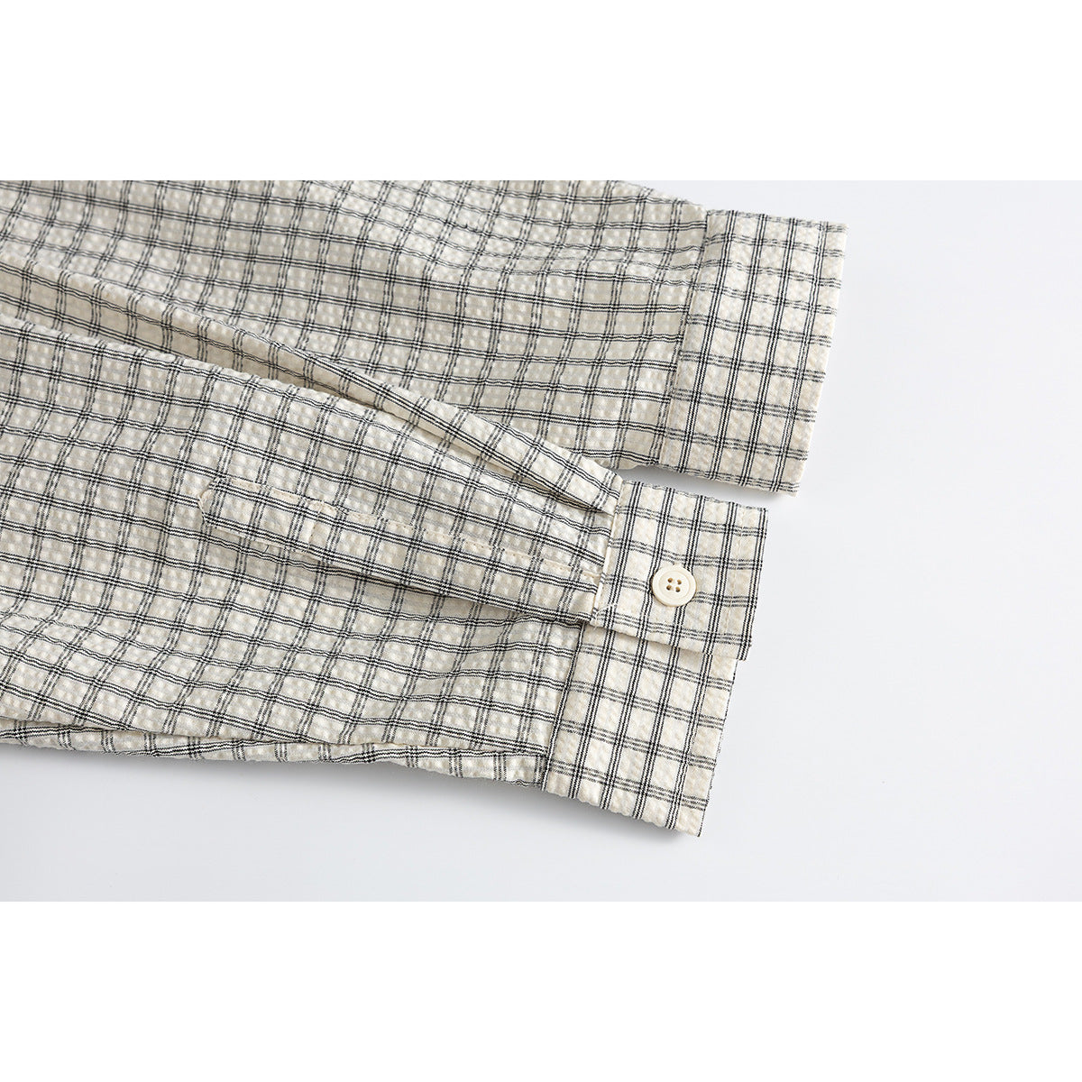 Close-up of the cream plaid shirt's long sleeve and buttoned cuff.
