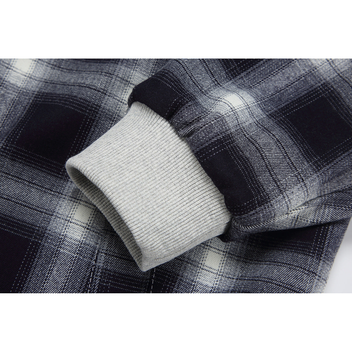 Close-up of a black-and-gray plaid hoodie sleeve and light gray ribbed cuff.