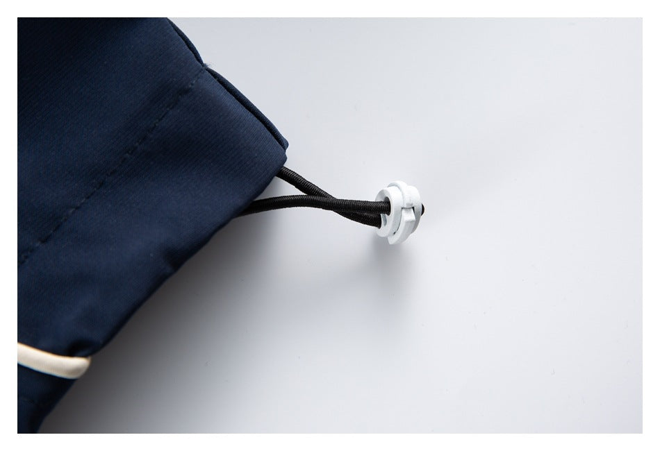Close-up of a navy garment hem with a black drawcord and white plastic toggle.