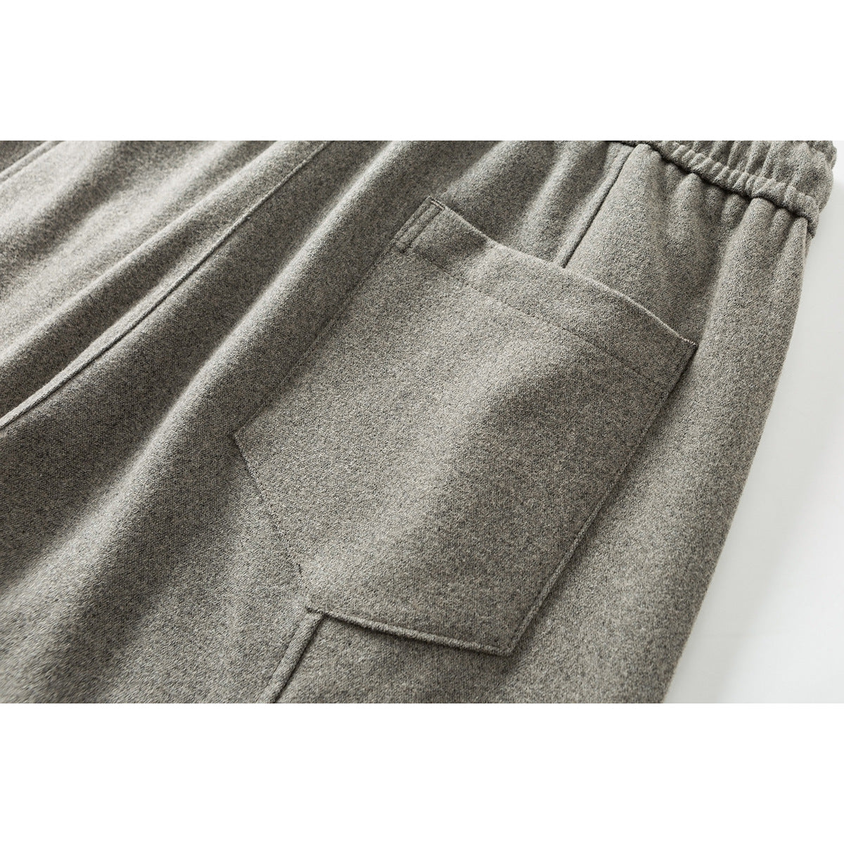 Close-up of gray pants showing a large patch pocket and elastic waistband.