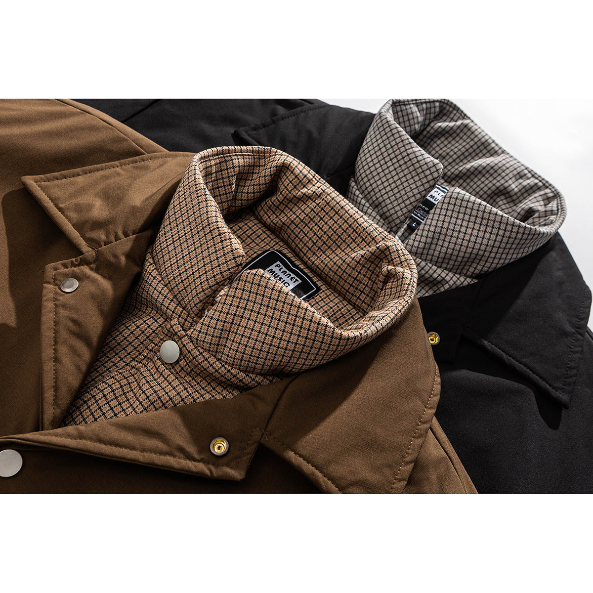 Close-up of brown and black jackets with checked inner collars and metal snaps.
