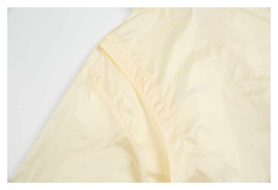 Close-up of a pale yellow garment seam with a tiny gray emblem.