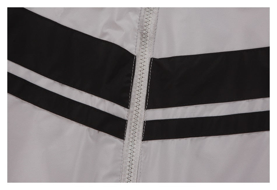 Close-up of a light gray garment zipper bordered by broad black and narrow gray horizontal stripes.