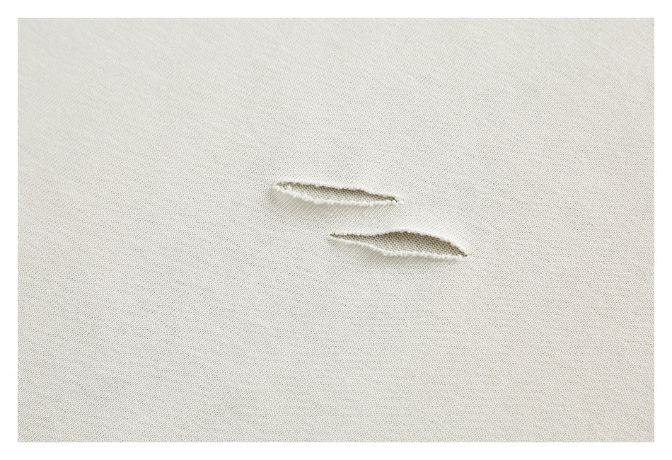 Close-up of two small horizontal slits in ivory fabric.