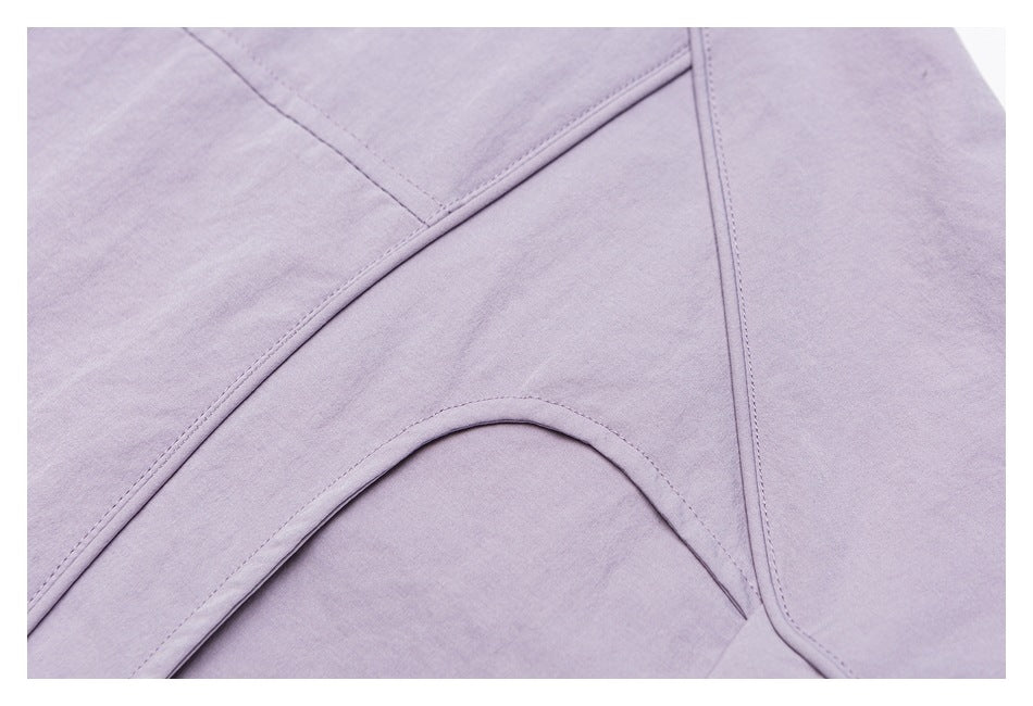 Close-up of pale lavender fabric showing curved panel seams and precise topstitching.