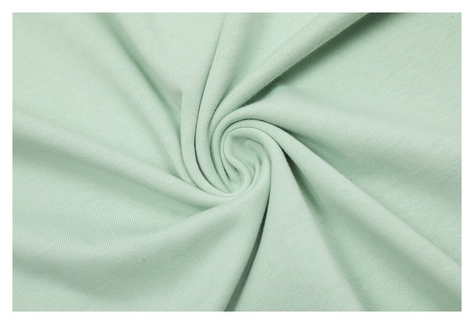 Pale mint-green fabric gathered into a swirl to show its surface and drape.
