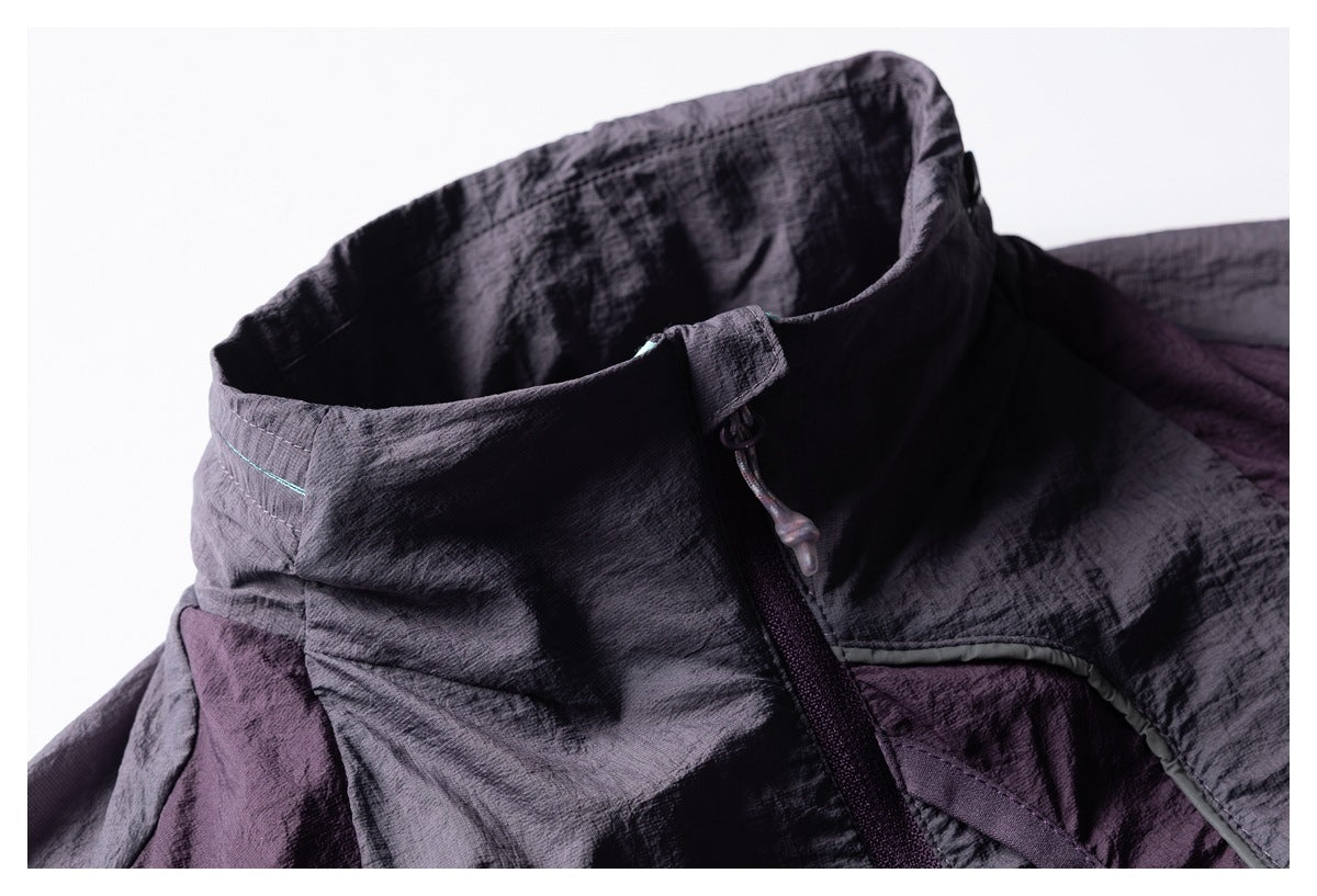 Close-up of the garment's high collar, front zipper pull, and contrasting purple-gray panels.