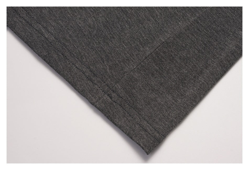 Close-up of a dark gray garment corner showing the fabric texture and double-stitched hem.